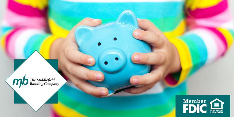 a child's hands holding a blue piggy bank